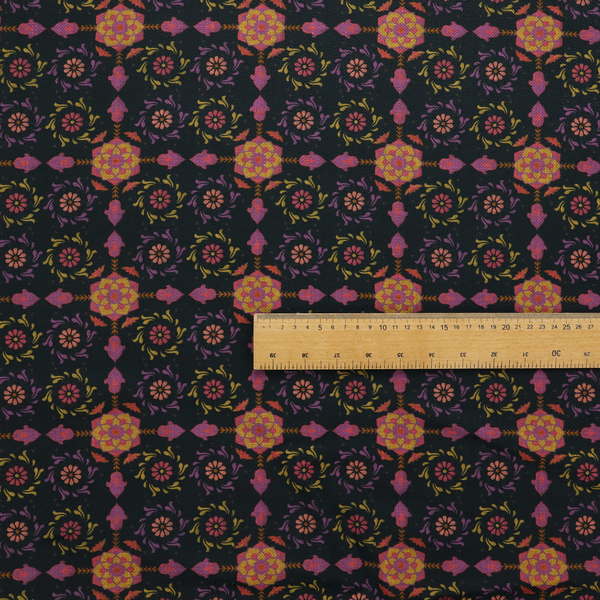 An intricate geometric fabric pattern featuring repeating mandala motifs, floral medallions, and ornate tiles in shades of pink, orange, yellow, and purple set against a dark black background.