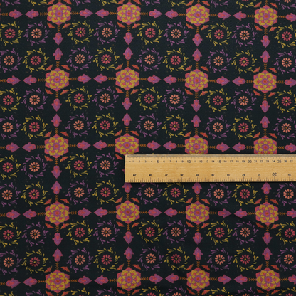 An intricate geometric fabric pattern featuring repeating mandala motifs, floral medallions, and ornate tiles in shades of pink, orange, yellow, and purple set against a dark black background.