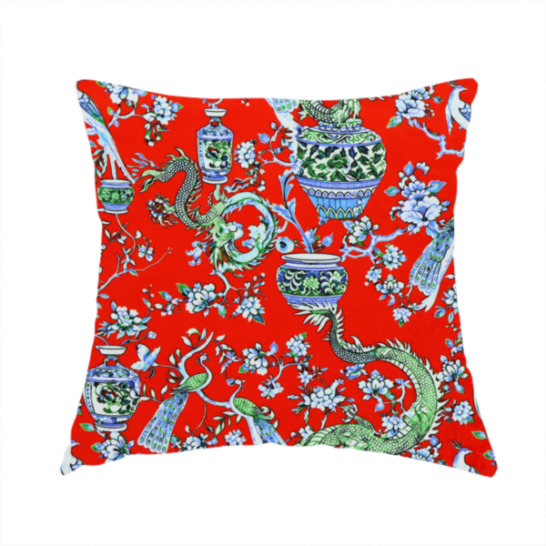 The fabric used to create this handmade cushion is a vibrant red Chinoiseries fabric featuring an intricate pattern of green dragons, elegant peacocks, blue-and-white porcelain vases, and blossoming floral branches.