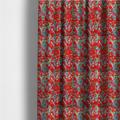 The fabric used to create these made-to-measure curtains is a vibrant red Chinoiseries fabric featuring an intricate pattern of green dragons, elegant peacocks, blue-and-white porcelain vases, and blossoming floral branches.
