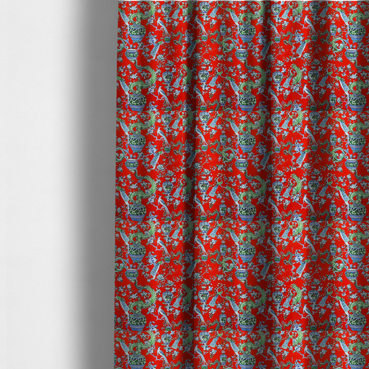 The fabric used to create these made-to-measure curtains is a vibrant red Chinoiseries fabric featuring an intricate pattern of green dragons, elegant peacocks, blue-and-white porcelain vases, and blossoming floral branches.