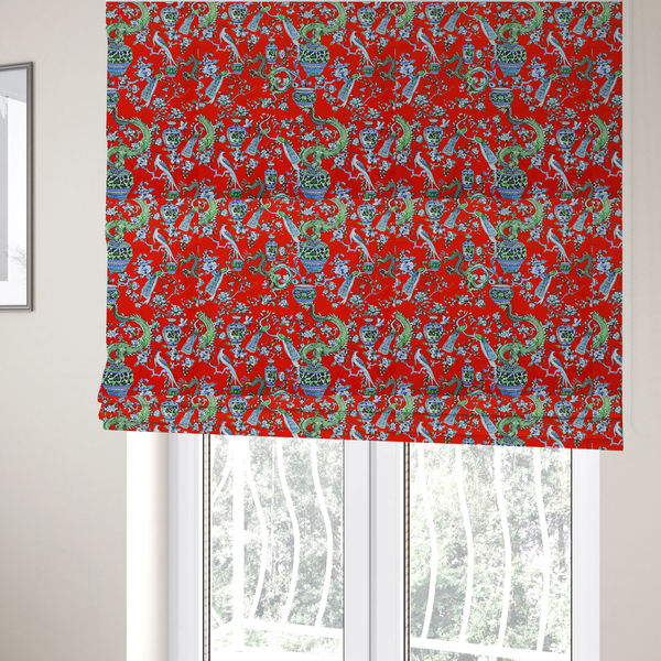 The fabric used to create these Roman blinds is a vibrant red Chinoiseries fabric featuring an intricate pattern of green dragons, elegant peacocks, blue-and-white porcelain vases, and blossoming floral branches.