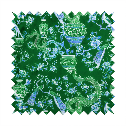Emerald green fabric featuring a repeating Chinoiserie pattern with light green dragons, blue and white porcelain vases, perched peacocks, and floral branches.   