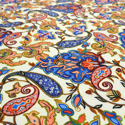Cream-coloured fabric with an ornate repeating paisley pattern showcasing royal blue tear-drop motifs, vibrant coral and orange florals, and flowing leafy vines.   
