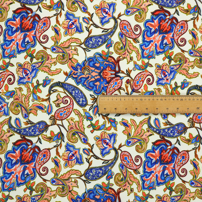 Cream-coloured fabric with an ornate repeating paisley pattern showcasing royal blue tear-drop motifs, vibrant coral and orange florals, and flowing leafy vines.   