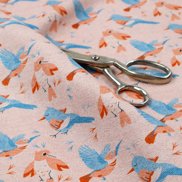 This fabric includes blue and pink birds in various positions on a soft pink background.