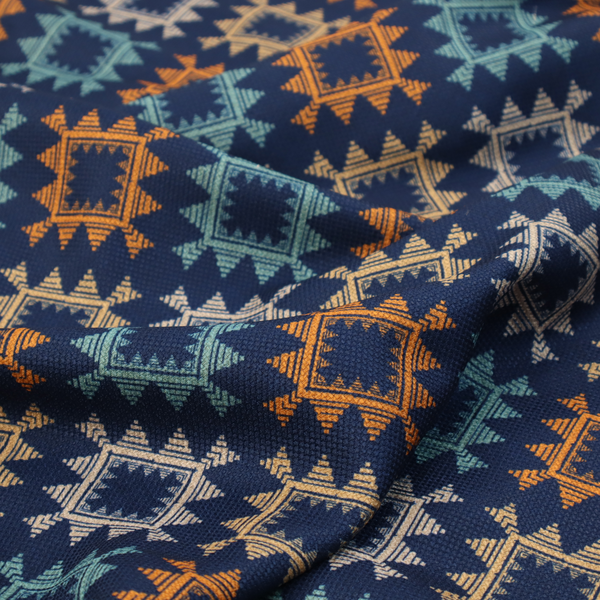 This fabric features repeated geometric shapes in blues, oranges and pinks on a navy blue background.