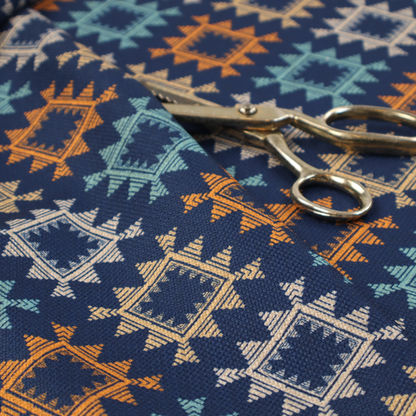 This fabric features repeated geometric shapes in blues, oranges and pinks on a navy blue background.