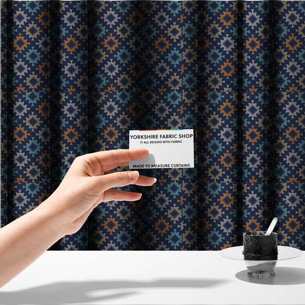The fabric used to create these made-to-measure curtains, features repeated geometric shapes in blues, oranges and pinks on a navy blue background.