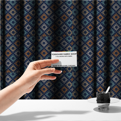 The fabric used to create these made-to-measure curtains, features repeated geometric shapes in blues, oranges and pinks on a navy blue background.