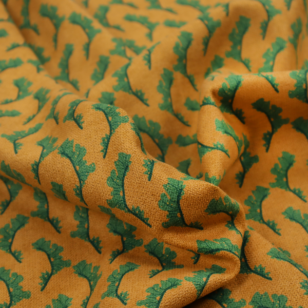 This fabric has a repeated green leaf/floral design on a warm yellow/golden background.