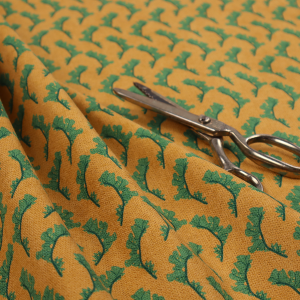 This fabric has a repeated green leaf/floral design on a warm yellow/golden background.