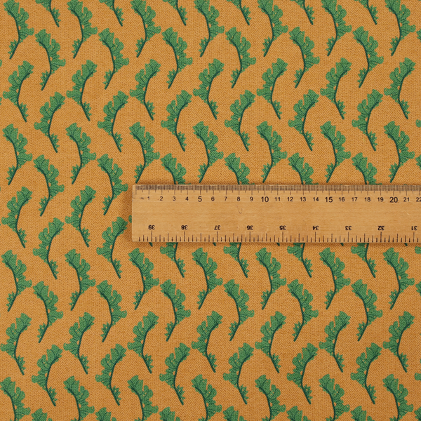 This fabric has a repeated green leaf/floral design on a warm yellow/golden background.