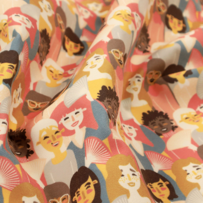 A whimsical, repeating fabric pattern featuring illustrated portraits of women with diverse hairstyles and accessories, some holding white hand fans, set against a warm coral-pink background.