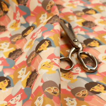 A whimsical, repeating fabric pattern featuring illustrated portraits of women with diverse hairstyles and accessories, some holding white hand fans, set against a warm coral-pink background.