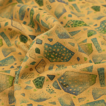 An earthy, abstract fabric pattern featuring organic mosaic shapes in moss green, teal, and slate grey on a textured mustard yellow background.