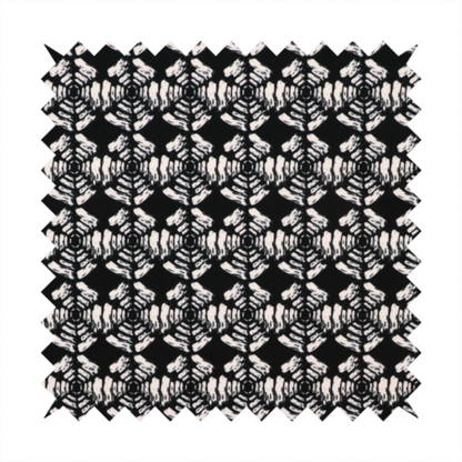 A bold, monochrome fabric pattern featuring a repeating hand-inked radial geometric design in cream on a solid black background.
