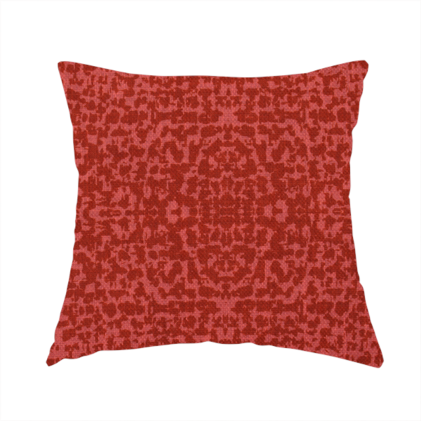 The fabric used to create this handmade cushion is a distressed terracotta red fabric with a symmetrical, abstract medallion pattern and a weathered, block-print texture.