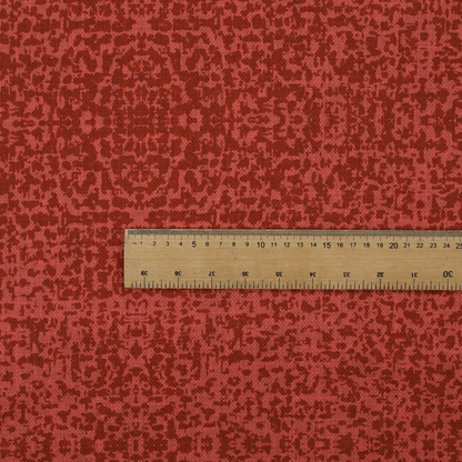 Distressed terracotta red fabric with a symmetrical, abstract medallion pattern and a weathered, block-print texture.
