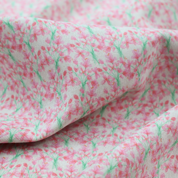 Vertical pink floral branch pattern on white fabric, featuring a delicate blossom and green stem motif.