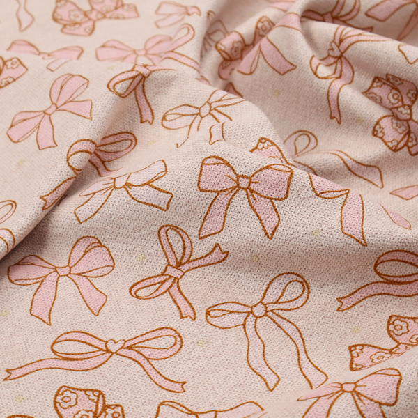 This fabric includes different shapes and styles of pink bows on a pink background.