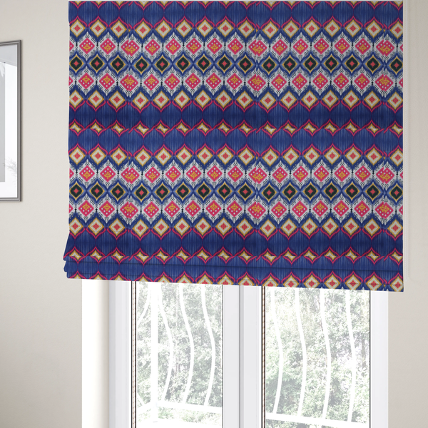 The fabric used to create these bespoke Roman blinds is a high-energy textile with a large-scale geometric Ikat design. The pattern showcases concentric diamonds with feathered, "blurred" edges in electric blue, bright pink, and yellow, set against a background with vertical white striations.