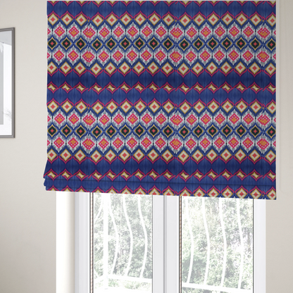 The fabric used to create these bespoke Roman blinds is a high-energy textile with a large-scale geometric Ikat design. The pattern showcases concentric diamonds with feathered, "blurred" edges in electric blue, bright pink, and yellow, set against a background with vertical white striations.