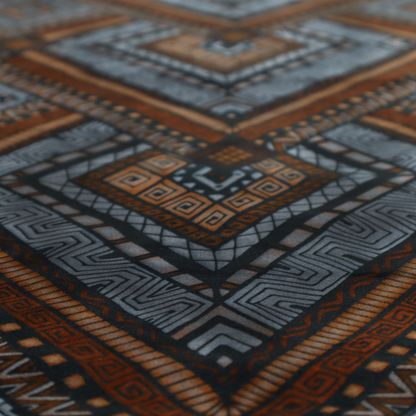 Intricate textile design with a repeating diamond and chevron motif. The pattern features fine, hand-inked linework, including Greek key patterns and zig-zags. The colour palette is a moody mix of earthy terracotta, deep grey, and black, giving it a rustic, bohemian feel.
