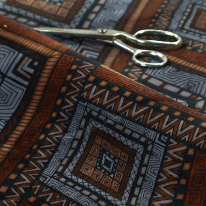 Intricate textile design with a repeating diamond and chevron motif. The pattern features fine, hand-inked linework, including Greek key patterns and zig-zags. The colour palette is a moody mix of earthy terracotta, deep grey, and black, giving it a rustic, bohemian feel.