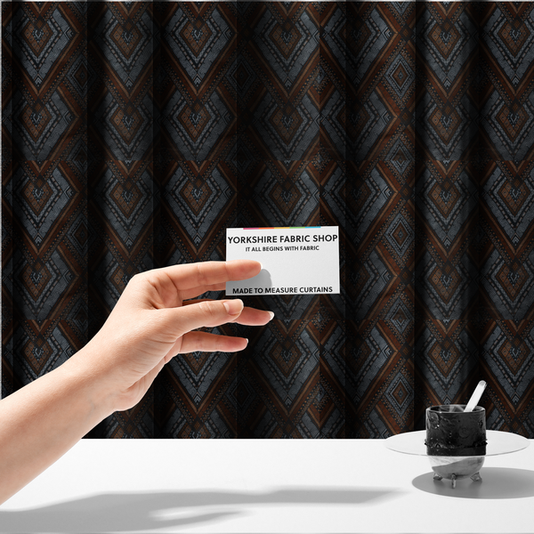 The fabric used to create these made-to-measure curtains is a intricate textile design with a repeating diamond and chevron motif. The pattern features fine, hand-inked linework, including Greek key patterns and zig-zags. The colour palette is a moody mix of earthy terracotta, deep grey, and black, giving it a rustic, bohemian feel.