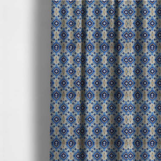 The fabric used to create these made-to-measure curtains is a repeating textile pattern featuring ornate blue Ikat medallions with a feathered, hand-painted appearance. The design includes smaller navy diamonds and sandy beige geometric shapes set against a light oatmeal-coloured fabric texture.