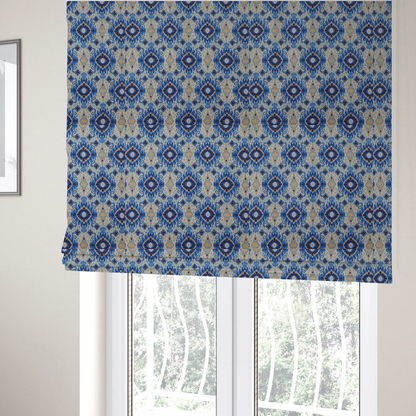 The fabric used to create these bespoke Roman blinds is a repeating textile pattern featuring ornate blue Ikat medallions with a feathered, hand-painted appearance. The design includes smaller navy diamonds and sandy beige geometric shapes set against a light oatmeal-coloured fabric texture.