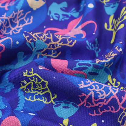 A vibrant nautical pattern featuring pink octopuses, yellow coral branches, and textured sea sponges set against an electric indigo blue background.