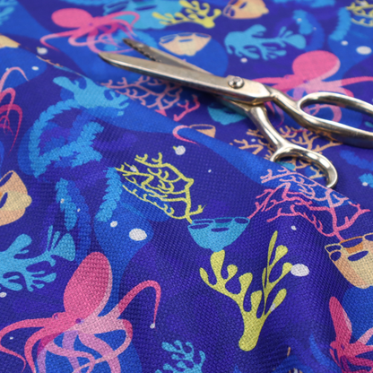 A vibrant nautical pattern featuring pink octopuses, yellow coral branches, and textured sea sponges set against an electric indigo blue background.