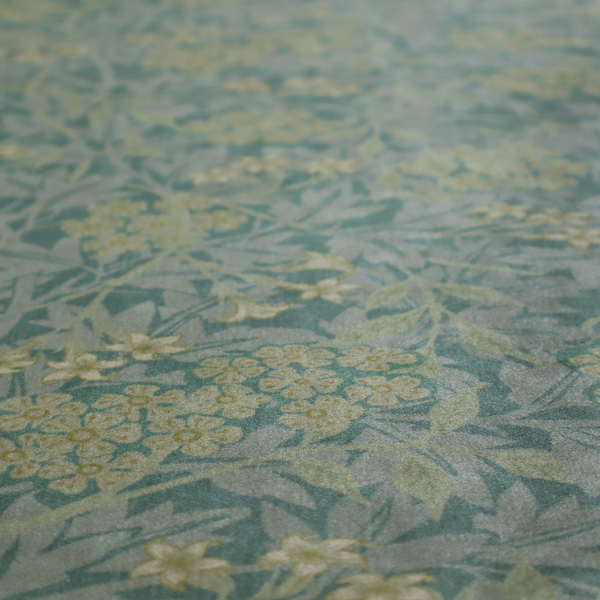 Muted green textile print with a complex, repeating botanical motif. The design features tightly packed five-petal flower clusters and delicate willow-like leaves in shades of dusty sage, teal, and pale lime green.