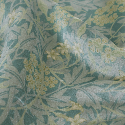 Muted green textile print with a complex, repeating botanical motif. The design features tightly packed five-petal flower clusters and delicate willow-like leaves in shades of dusty sage, teal, and pale lime green.