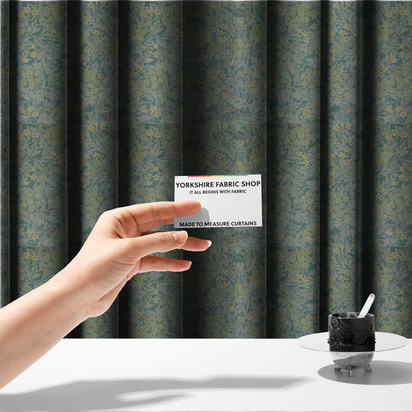 The fabric used for these made-to-measure curtains is a muted green textile print with a complex, repeating botanical motif. The design features tightly packed five-petal flower clusters and delicate willow-like leaves in shades of dusty sage, teal, and pale lime green.