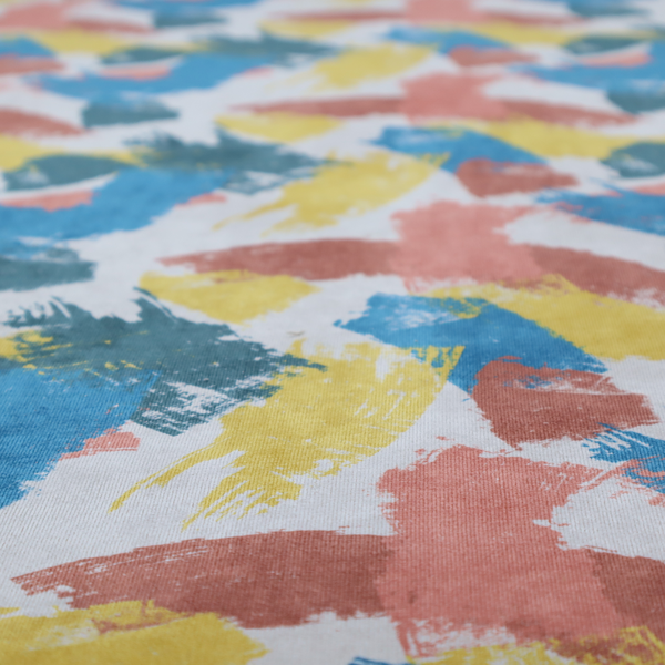 Vibrant textile print featuring large, expressive paint swipes in cornflower blue, sunny yellow, terracotta red, and dark teal. The brushstrokes overlap to create a sense of movement and have a visible, dry-brush texture with distressed edges.