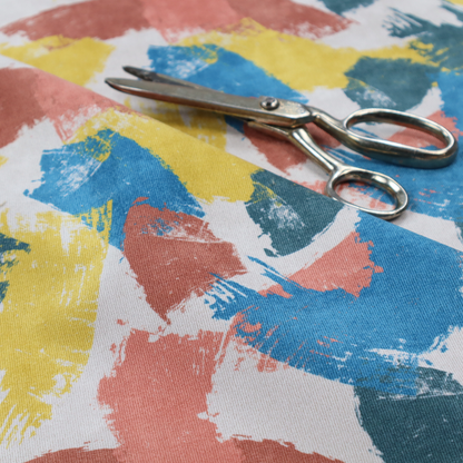Vibrant textile print featuring large, expressive paint swipes in cornflower blue, sunny yellow, terracotta red, and dark teal. The brushstrokes overlap to create a sense of movement and have a visible, dry-brush texture with distressed edges.
