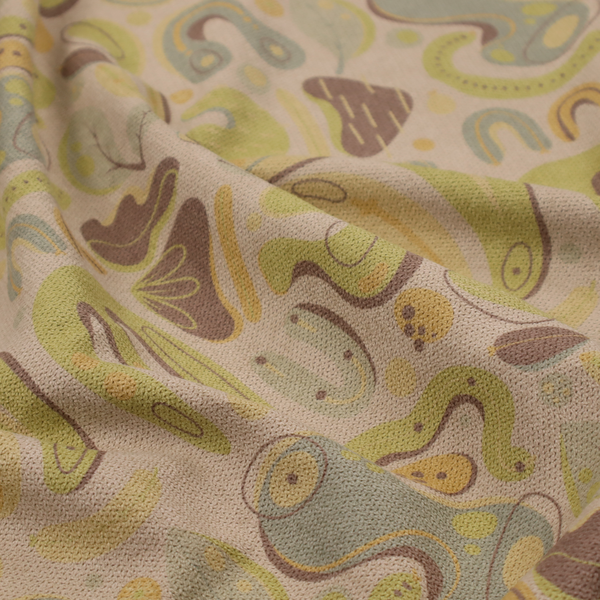 An abstract repeating pattern on a beige fabric background, featuring organic, amoeba-like shapes in earthy tones of olive green, muted yellow, and light brown. The design includes various fluid forms: U-shapes, elongated ovals, leaf-like outlines, and speckled pods. Some shapes are solid, while others contain interior lines, dots, or smaller concentric forms, creating a playful, mid-century modern or retro aesthetic with a soft, matte textile texture.