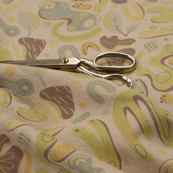 An abstract repeating pattern on a beige fabric background, featuring organic, amoeba-like shapes in earthy tones of olive green, muted yellow, and light brown. The design includes various fluid forms: U-shapes, elongated ovals, leaf-like outlines, and speckled pods. Some shapes are solid, while others contain interior lines, dots, or smaller concentric forms, creating a playful, mid-century modern or retro aesthetic with a soft, matte textile texture.
