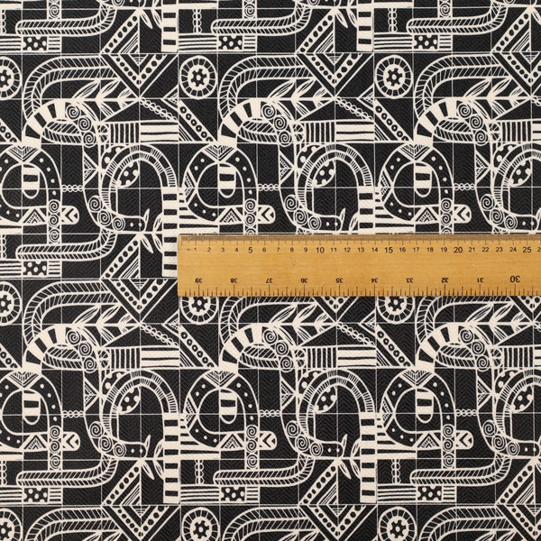An intricate black and white repeating pattern featuring a grid of tribal-inspired geometric motifs. The design displays stylized, interlocking serpentine and curved forms filled with detailed line work, dots, and hatch marks. Circular gear-like symbols and triangular accents create a structured, rhythmic composition with a high-contrast, hand-drawn aesthetic on a textured fabric.