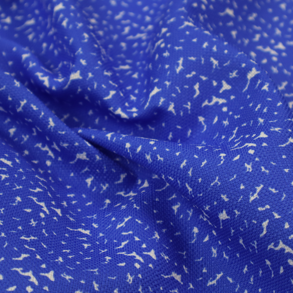 A bright cobalt blue fabric with a dense, non-directional "speckle" or "splatter" pattern.
