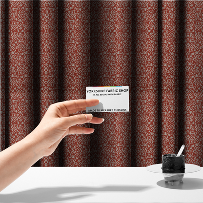 The fabric used to create these made-to-measure curtains is a decorative textile featuring a symmetrical, kaleidoscopic pattern in red and beige. The intricate, interlocking organic shapes create a dense, filigree-like design with a slightly weathered or distressed look. The fabric has a visible, fine-textured weave that gives the pattern a soft, matte appearance.