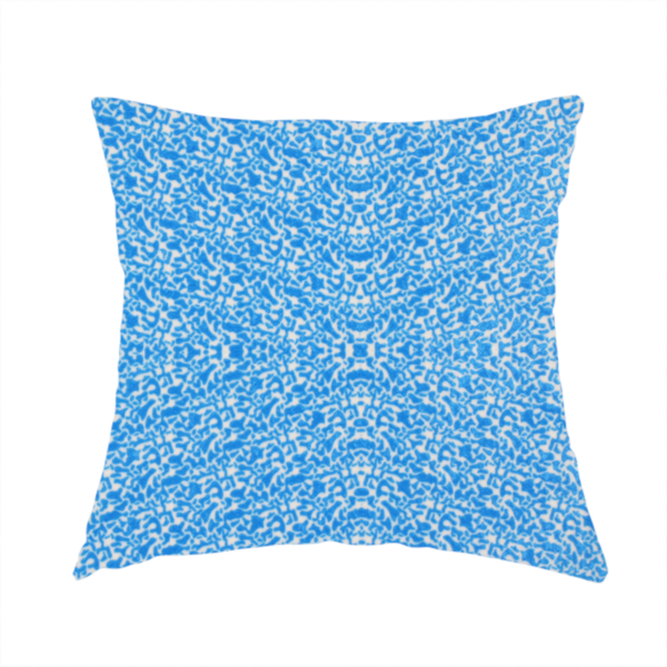 The fabric used to create this handmade cushion is a symmetrical, kaleidoscopic textile pattern in bright azure blue and white. The design features intricate, interlocking organic shapes mirrored vertically and horizontally to create a dense, mosaic-like filigree across the fabric.