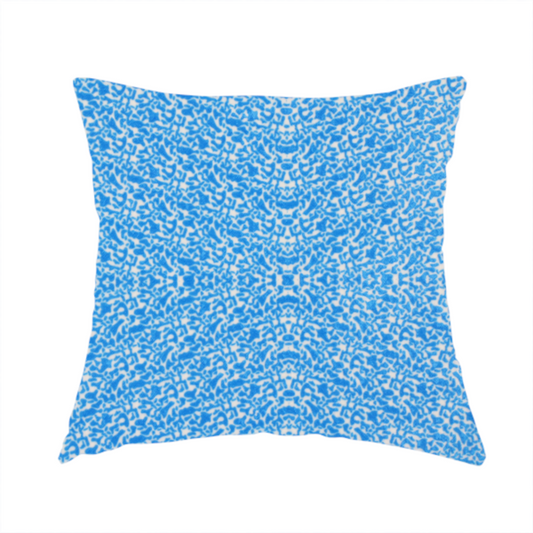 The fabric used to create this handmade cushion is a symmetrical, kaleidoscopic textile pattern in bright azure blue and white. The design features intricate, interlocking organic shapes mirrored vertically and horizontally to create a dense, mosaic-like filigree across the fabric.