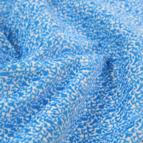 This fabric is a symmetrical, kaleidoscopic textile pattern in bright azure blue and white. The design features intricate, interlocking organic shapes mirrored vertically and horizontally to create a dense, mosaic-like filigree across the fabric.