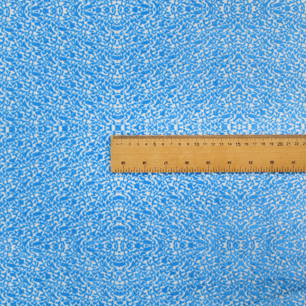 This fabric is a symmetrical, kaleidoscopic textile pattern in bright azure blue and white. The design features intricate, interlocking organic shapes mirrored vertically and horizontally to create a dense, mosaic-like filigree across the fabric.