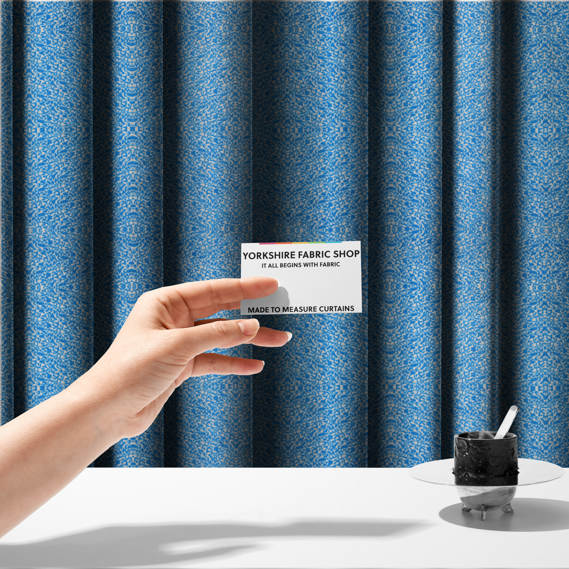 The fabric used to create these made-to-measure curtains is a symmetrical, kaleidoscopic textile pattern in bright azure blue and white. The design features intricate, interlocking organic shapes mirrored vertically and horizontally to create a dense, mosaic-like filigree across the fabric.