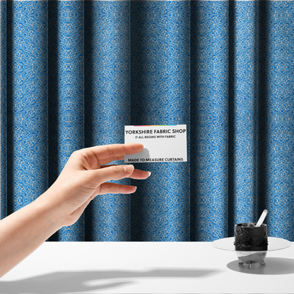 The fabric used to create these made-to-measure curtains is a symmetrical, kaleidoscopic textile pattern in bright azure blue and white. The design features intricate, interlocking organic shapes mirrored vertically and horizontally to create a dense, mosaic-like filigree across the fabric.